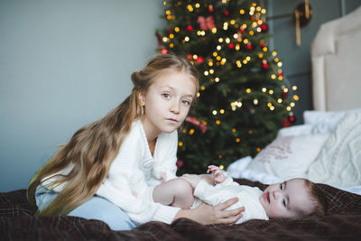 Portrait of young woman sitting on bed at home