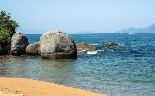 Rocks on sea shore against sky