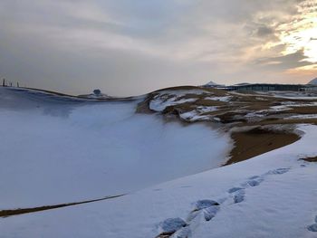 Scenic view of snow covered land against sky during sunset