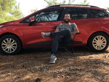 Portrait of young man sitting on car