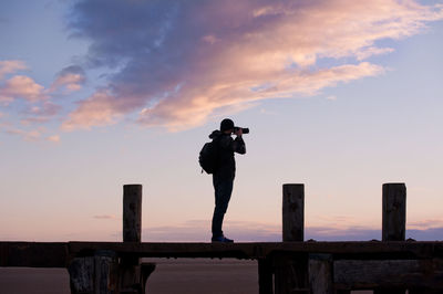 Full length of man taking picture while standing on footbridge