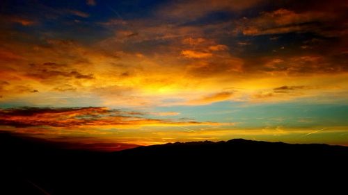 Silhouette landscape against dramatic sky during sunset