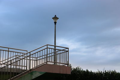 Low angle view of street light by building against sky