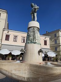 Low angle view of statue against building in city