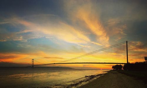 Scenic view of suspension bridge over sea during sunset