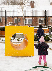 Rear view of boy and girl standing on snow