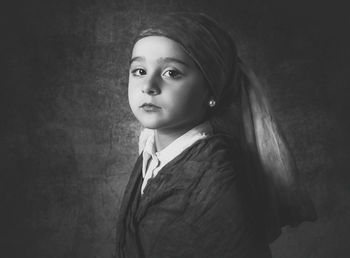 Portrait of young woman standing against black background