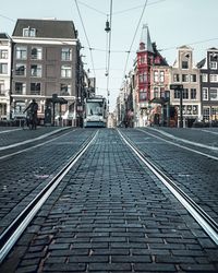 Railroad tracks amidst buildings in city against sky