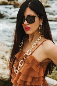 Portrait of young woman wearing sunglasses standing at beach