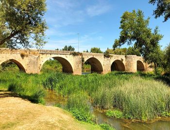 Arch bridge over river against sky