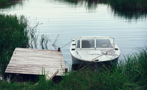 Boat moored on field by lake