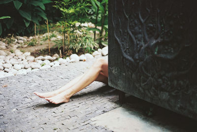 Low section of woman relaxing on footpath