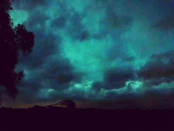 Low angle view of dramatic sky over silhouette landscape