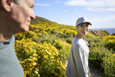 Smiling woman looking at man while walking on mountain against sky