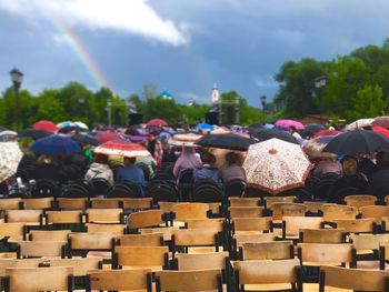 Rear view of people holding umbrellas while siting on chairs at event