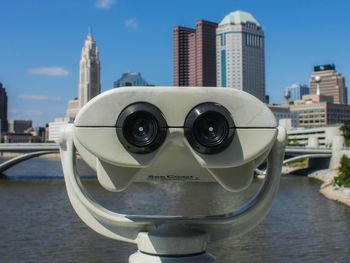 Close-up of coin operated binoculars with city in background
