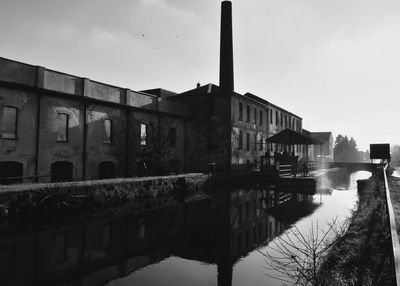 Bridge over river by buildings against sky