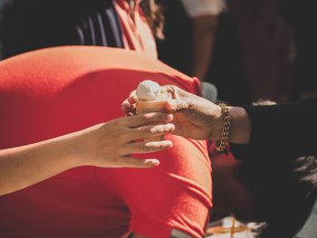 Close-up of people hands holding ice cream against man 