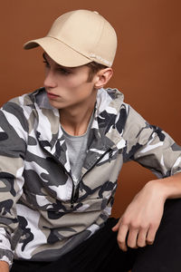 Midsection of boy wearing hat sitting against wall