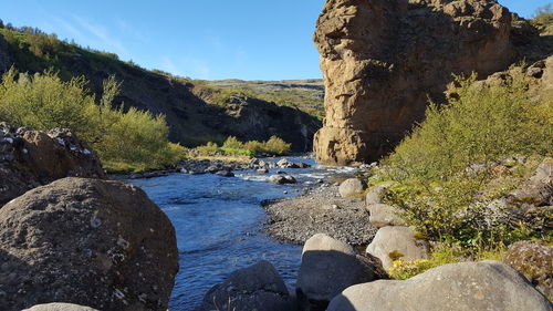 Stream flowing through rocks against sky