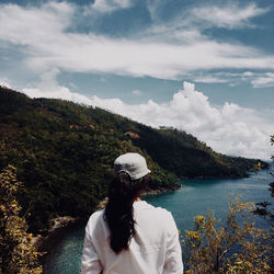 Rear view of woman looking at waterfall against sky