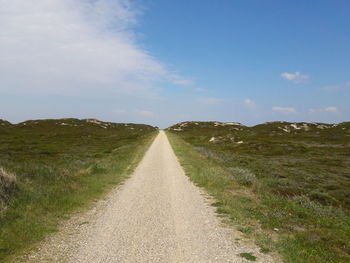 Footpath amidst field against sky
