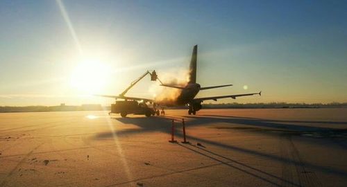 Airplane on airport runway against sky during sunset