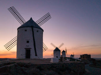 Traditional windmill against sky at sunset