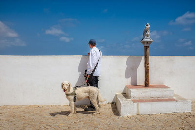 Man standing by dog against sky