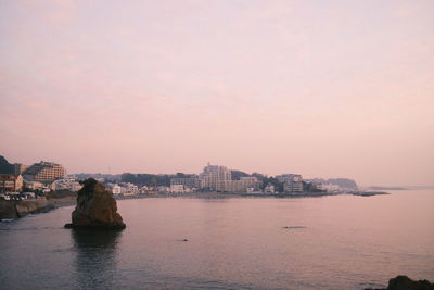 City by sea against sky at dusk