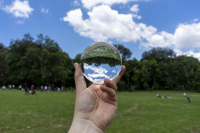 Midsection of person holding crystal ball against trees