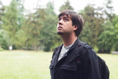Close-up of young man standing against trees