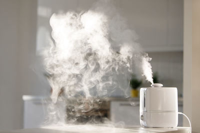 Close-up of smoke emitting from glass on table