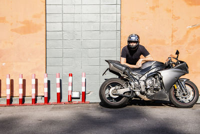 Man leaning on his motorcycle in front of warehouse in bangkok