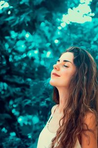Woman looking away against trees