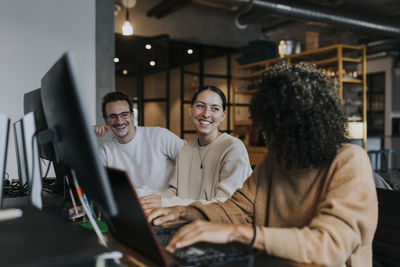 Female computer programmer discussing strategy with happy colleagues at startup company