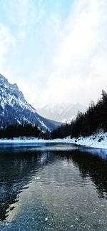 Scenic view of lake by snowcapped mountains against sky