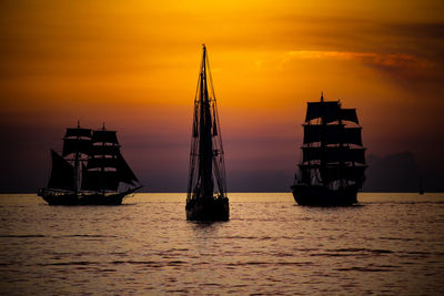 Silhouette sailboats in sea against sky during sunset