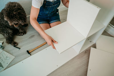 Midsection of woman with dog working on wood at home