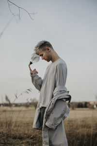 Young man with light bulb standing on field