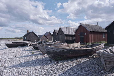 Boats moored on beach by buildings against sky