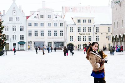 Portrait of woman standing against buildings during winter in city