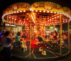 Illuminated carousel in amusement park at night