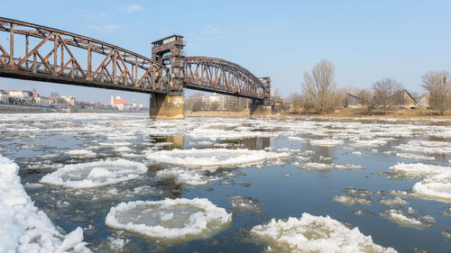 Bridge over river against sky during winter