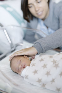 Woman with sleeping newborn baby in hospital