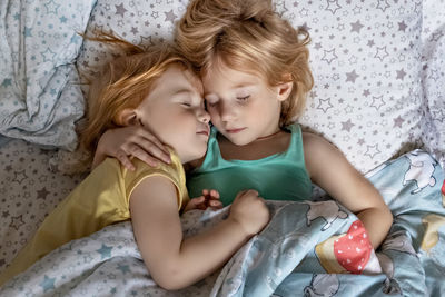 High angle view of sisters sleeping on bed at home