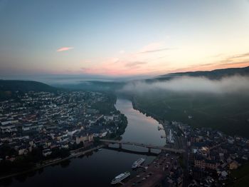 High angle view of mosel river and buildings against sky during sunrise at bernkastel-kues