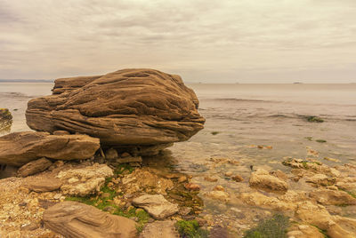 Rock formation on beach against sky