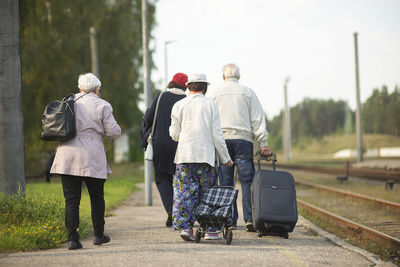 Rear view of a group of seniors elderly old people with luggage waiting for a train to travel