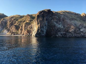 Scenic view of rocks in sea against clear sky